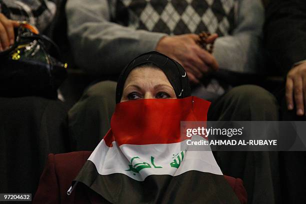 An Iraqi teacher covers her face with a national flag as she attends a ceremony on the occasion of the Teachers Day at a sports stadium in Baghdad on...