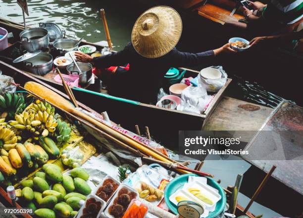 woman sells food from boat on floating market in bangkok, thailand - bangkok floating market stock pictures, royalty-free photos & images