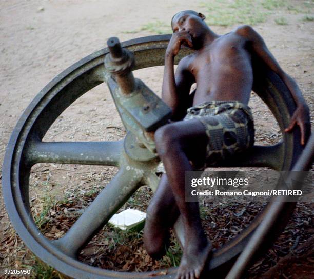 Biafra, a disabled serviceman, his right foot missing, lays on a woodden wheel.