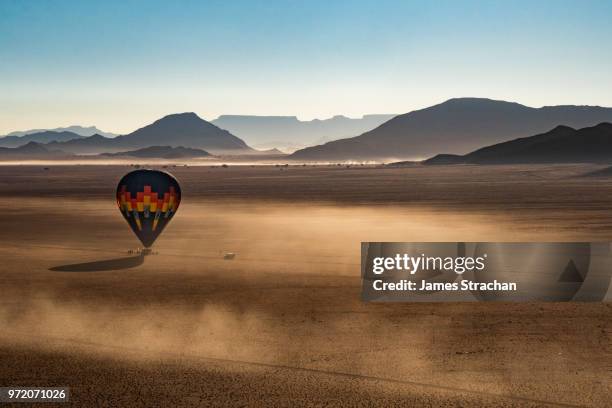 aerial view from a balloon of another balloon landing in the sossusvlei area at dawn near to pick-up vehicle, in dust-blown namib desert, namib-naukluft, namibia (property release) - permanence stock pictures, royalty-free photos & images