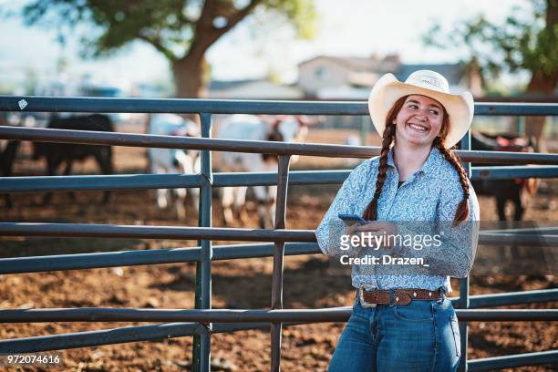 redhead cowgirl at ranch using smart phone - cattle call stock pictures, royalty-free photos & images