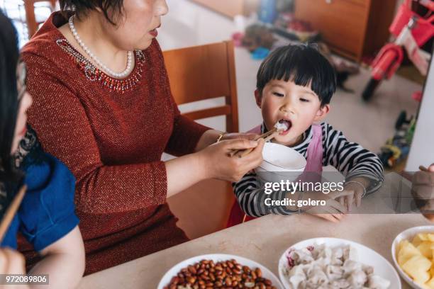 chinese grootmoeder voeding kleindochter - chinese kid stockfoto's en -beelden