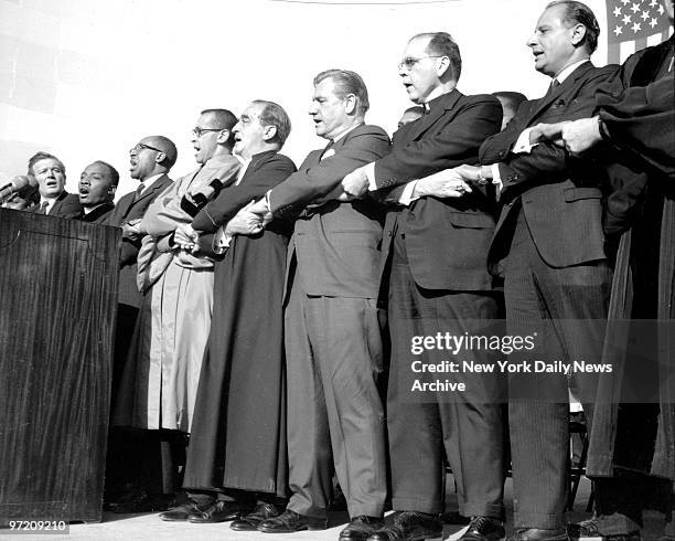 After memorial service in Central Park clergymen and officials injoin hands and sing, fromt left: Mayor John Lindsay, the Rev. William James, The...