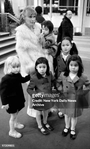Actress Mia Farrow and five of her seven children enjoy winter sunshine. Mia holds Misha and next to Mia stands Soon-Yi Previn. In front are...