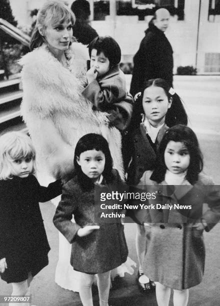 Actress Mia Farrow and five of her seven children enjoy winter sunshine. Mia holds Misha and next to Mia stands Soon-Yi Previn. In front are...