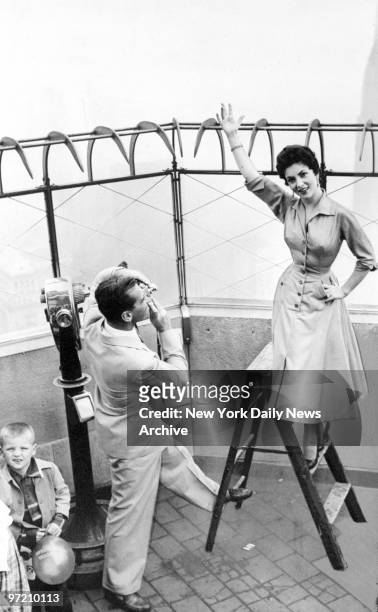 Actress Gina Lollobrigida poses for her husband, Dr. Milko Skofic, on top of the Empire State Building, while William J. Keary, president of the...