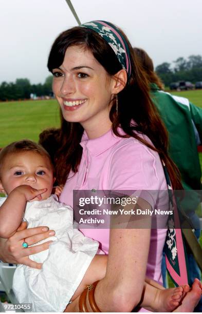 Actress Anne Hathaway cuddles Charly Ann, a friend's baby, during the first day of the annual Mercedes-Benz Polo Challenge at the Bridgehampton Polo...