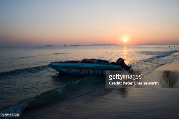 Tourist speedboat is anchored on the beach at sunset.