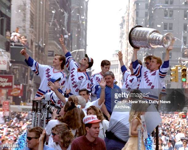 Adam Graves and Captain Mark Messier with Ranger teammates' ride through the Canyon of Heroes raising the Stanley Cup aloft, are swept up in a swirl...