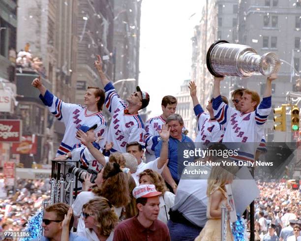 Adam Graves and Captain Mark Messier with Ranger teammates' ride through the Canyon of Heroes raising the Stanley Cup aloft, are swept up in a swirl...
