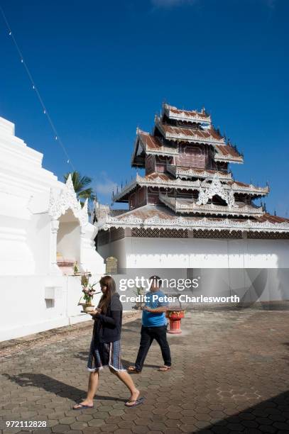 Thai Buddhists carry offerings to make merit as they walk past the main chedi at Wat Phra That Doi Kong Mu temple overlooking Mae Hong Son.