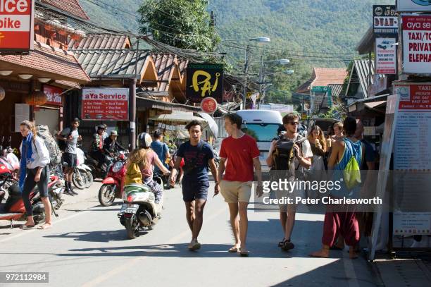 Tourists walk down a small street in the ever growing town of Pai, once a small village in the mountains of northern Thailand, now a tourist...