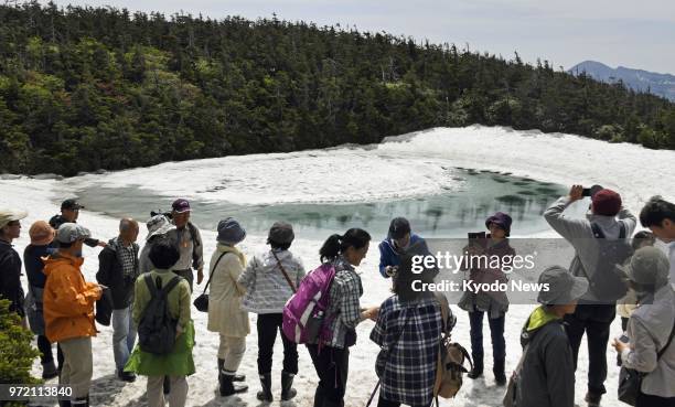 Tourists assemble around the "Hachimantai Dragon's Eye," a large area of ice surrounded by water, at the Kagaminuma Pond near Mt. Hachimantai's...