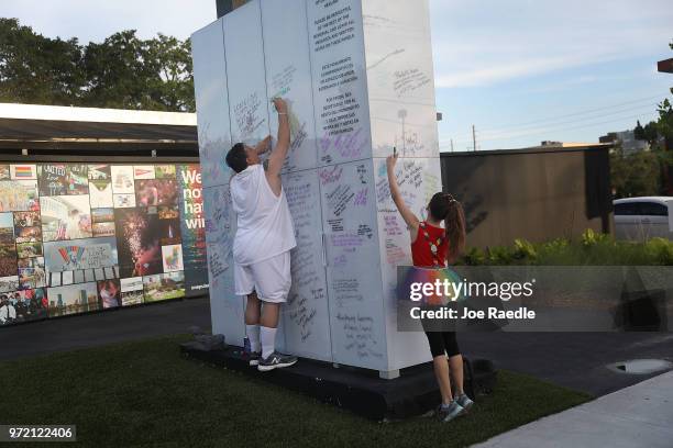 Jim McDermott and Isabella Andriolo write messages on the Pulse sign as they visit the memorial to the 49 shooting victims setup at the Pulse...