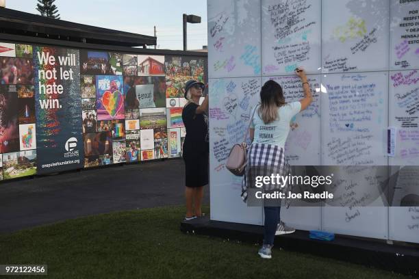 Sandy Bruno and Sondra Rae write messages on the Pulse sign as they visit the memorial to the 49 shooting victims setup at the Pulse nightclub where...