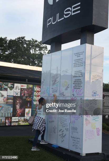 Sondra Rae writes a message on the Pulse sign as she visits the memorial to the 49 shooting victims setup at the Pulse nightclub where the shootings...