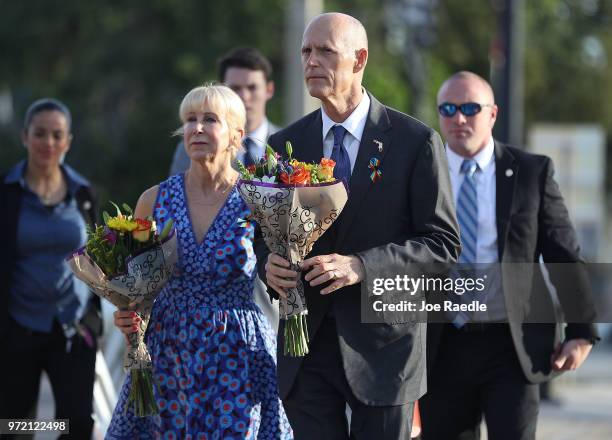 Florida Governor Rick Scott and First Lady Ann Scott carry flowers as they visit the memorial to the 49 shooting victims setup at the Pulse nightclub...