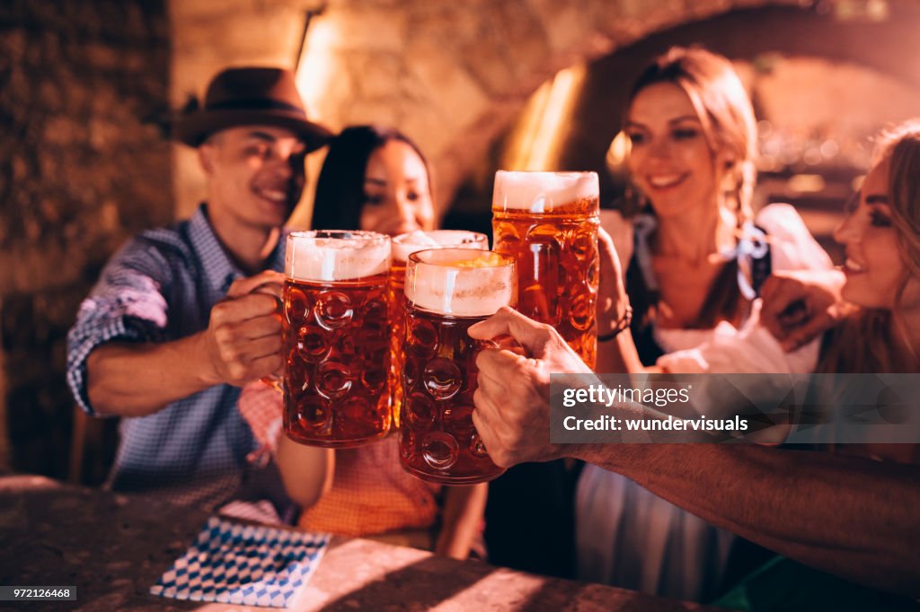 Amigos felices celebrando el Oktoberfest y brindando con cerveza