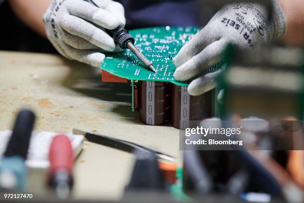 An employee solders a circuit board on the air conditioning fan assembly line at the EBM-Papst GmbH ventilation systems factory in Mulfingen,...