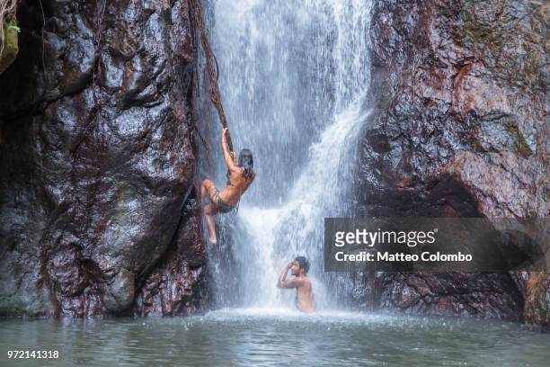 woman climbing on the side of a waterfall in an island, fiji - fiji stockfoto's en -beelden