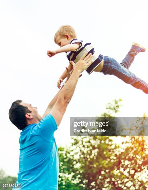 father throwing child in the air - ivanjekic stock pictures, royalty-free photos & images