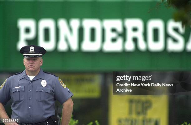 Police officer stands outside the Ponderosa steakhouse in Ashland, Va., where a man was shot Saturday night. Investigators, acting on the assumption...