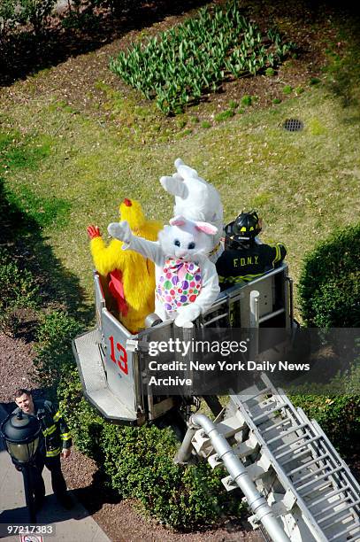 Firefighter dressed as the Easter Bunny is lifted up by ladder truck to entertain hospitalized children at New York-Presbyterian Weill Cornell...