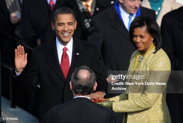 Beaming Barack Obama is sworn in as America's 44th President by Supreme Court Chief Justice John Roberts, as First Lady Michelle Obama holds the...