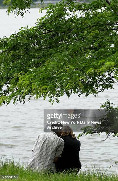 Couple spends a peaceful afternoon on the bank of the Hudson River in Riverside Park during the long Memorial Day weekend.