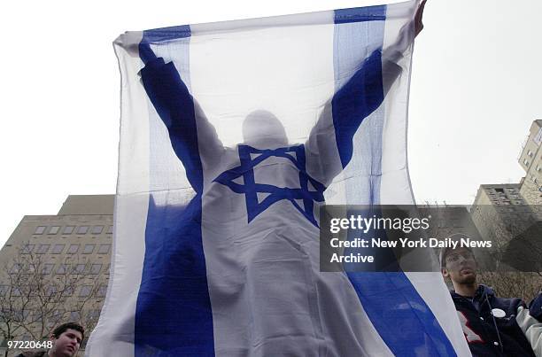 Demonstrator raises the Israeli flag in a pro-Israel rally at Dag Hammarskjold Plaza, 47th St. And First Ave.