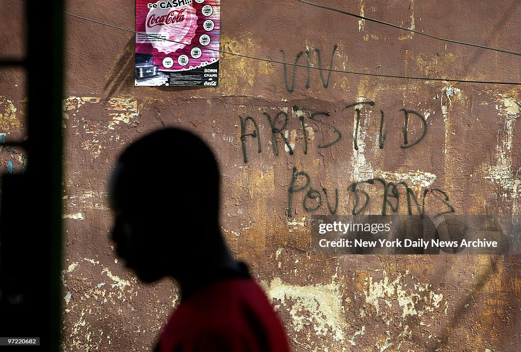 A young man walks past pro-Aristide graffiti on a wall in Po
