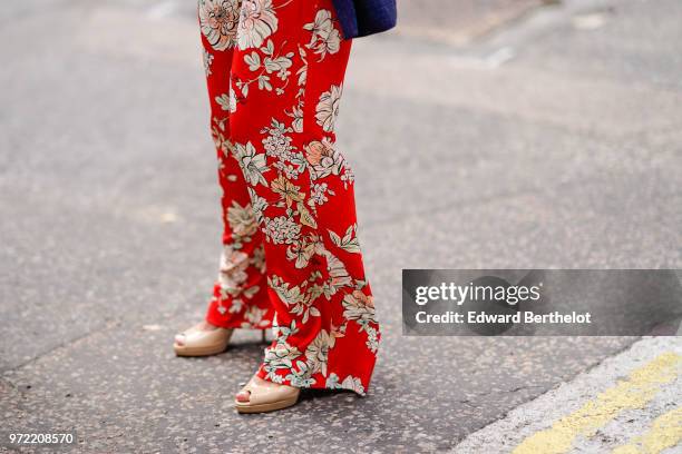 Guest wears red flower print flared pants, during London Fashion Week Men's June 2018 on June 09, 2018 in London, England.