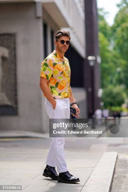 Guest wears a shirt with printed fruits , white pants, black shoes, sunglasses, during London Fashion Week Men's June 2018 on June 09, 2018 in...