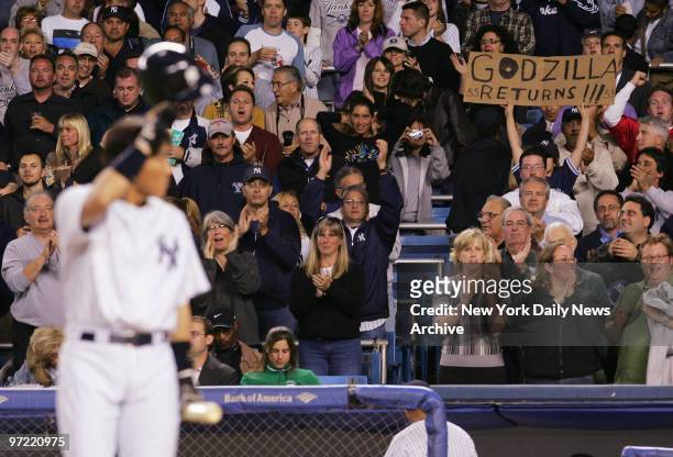 Fan at Yankee Stadium holds up a sign reading "Godzilla Returns" as New York Yankees' Hideki Matsui tips his cap while heading to bat in the first...