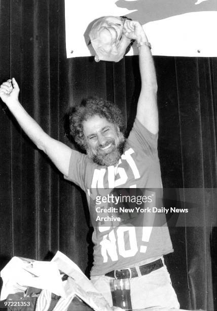 Abbie Hoffman holding a Ronald Reagan mask by the nose, after his keynote speech at the CMJ Music Marathon. Hoffman's shirt is in reference to Nancy...