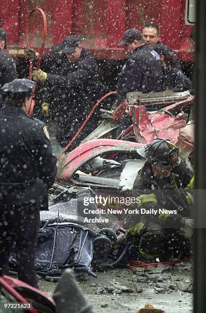 Firefighter sits next to a mangled stroller removed from the crumpled wreck of a minivan at 125th St. And First Ave. The auto was crushed, with the...