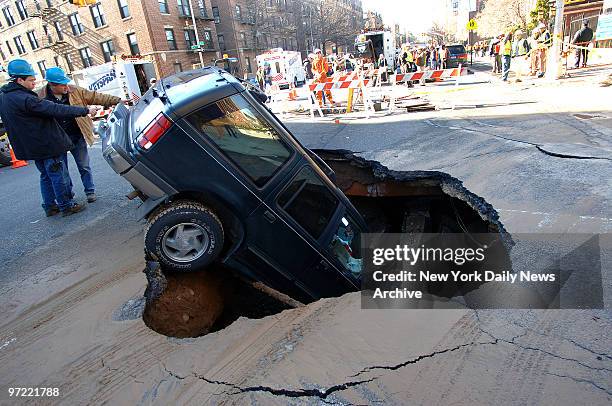 Ford Explorer sits nose-first inside a 15-foot-by-20-foot-wide sinkhole at the intersection of Fourth Ave. And 73rd St. In the Bay Ridge section of...