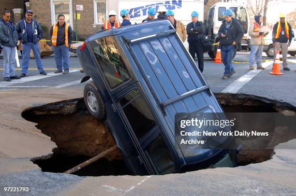 Ford Explorer sits nose-first inside a 15-foot-by-20-foot-wide sinkhole at the intersection of Fourth Ave. And 73rd St. In the Bay Ridge section of...