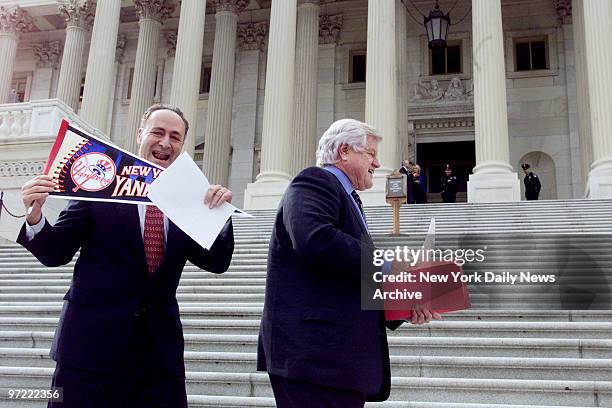 Gloating New York Sen. Chuck Schumer holds up a Yankees' pennant as Sen.Edward Kennedy turns away after paying off on his bet that the Boston Red Sox...