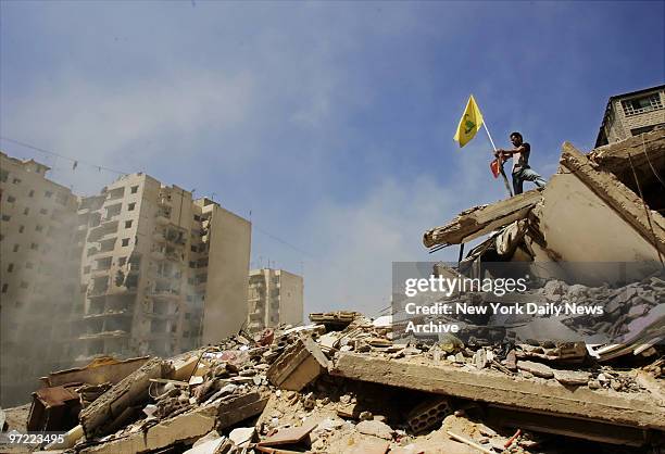 Lebanese man places a Hezbollah flag on top of a huge pile of rubble at a site in southern Beirut, Lebanon, where Israeli bombs leveled nine...