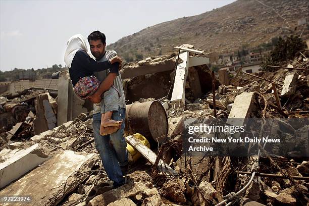 Man carries a disabled woman over the rubble in Aitaroun, Lebanon, only a few miles from the border with Israel, as flee their village after spending...