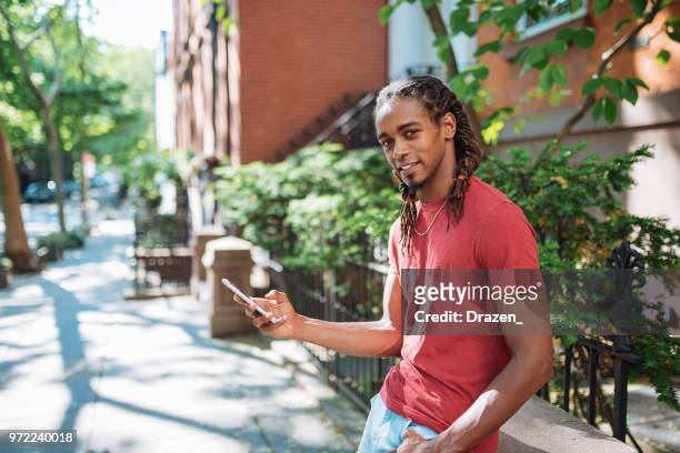 junge afro karibik kerl mit smartphone - afro caribbean and american stock-fotos und bilder