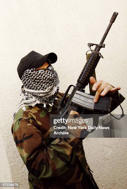 Masked Hezbollah fighter stands with an M-4 rifle that he says was taken from a dead Israeli soldier in Aita Ech Chaab, Lebanon, on the first day of...