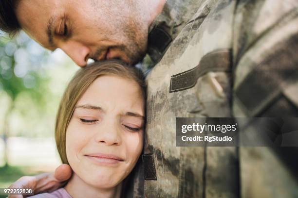 soldat se penchant sur sa fille triste en émotion - homecoming photos et images de collection