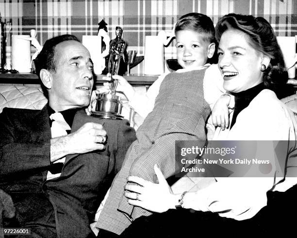 Actor Humphrey Bogart with his 3-Year-old-son Stephen [Stevie], holding his dads Academy Award "Oscar", along with his wife Actress Lauren Bacall.