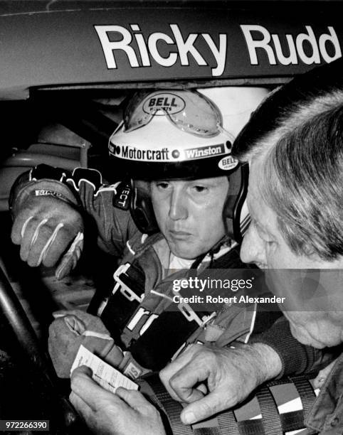 Driver Ricky Rudd sits in his car in the speedway garage as he talks with his car's owner, Bud Moore, during a practice session prior to the start of...