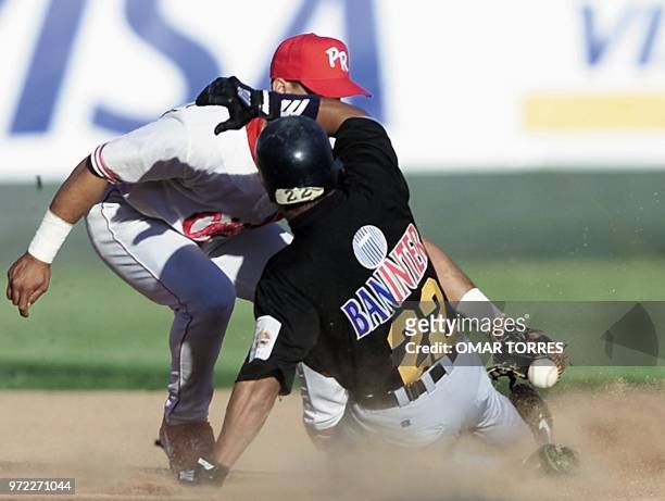 Luis Polonia, of the Aguilas de Cibao of the Dominican Republic falls as he get to the intermediate, guarded by Puerto Ricos' second baseman, Rico...