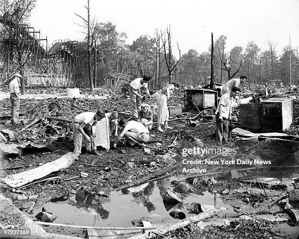 Amid the charred ruins of a penny arcade at Palisades Amusement Park, N.J., these people search for pennies. Three persons died of injuries in fire.