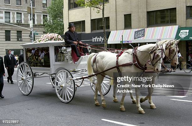 An antique glass-paneled carriage, pulled by a pair of cream-colored horses, bears the casket of R&B star Aaliyah along Madison Ave. From the Frank...