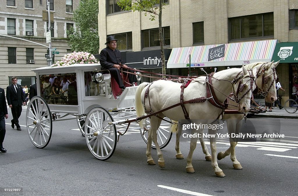 An antique glass-paneled carriage, pulled by a pair of cream